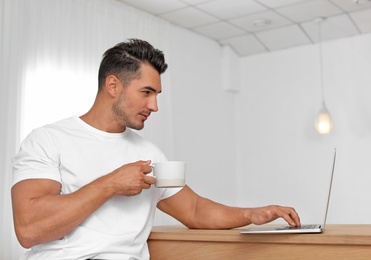 Portrait of handsome young man with laptop at home