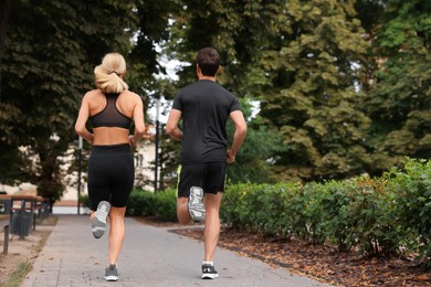 Photo of Healthy lifestyle. Couple running in park, back view with space for text