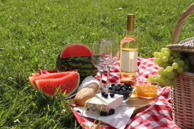 Photo of Picnic blanket with delicious food and wine outdoors on summer day