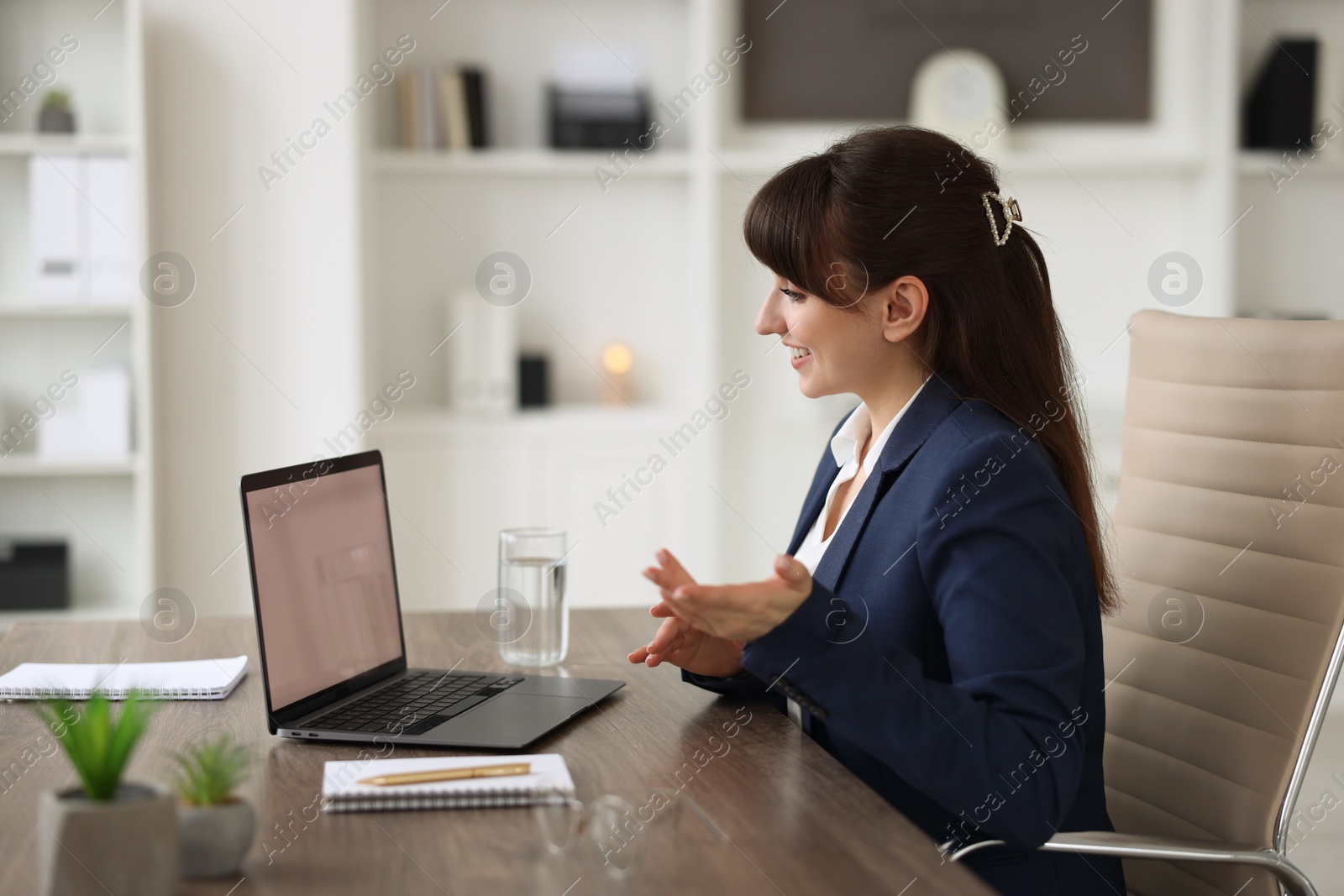 Photo of Woman using video chat during webinar at wooden table in office