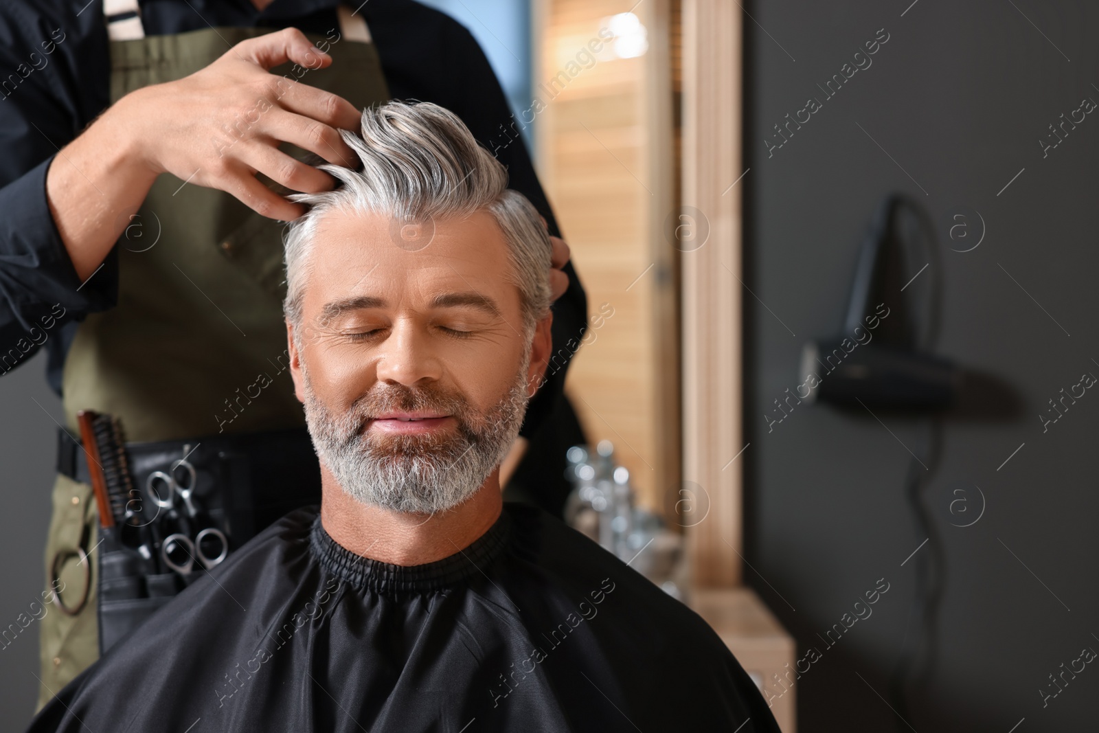 Photo of Hair styling. Professional hairdresser working with client in barbershop, closeup. Space for text