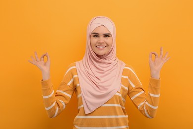 Photo of Portrait of Muslim woman in hijab meditating on orange background