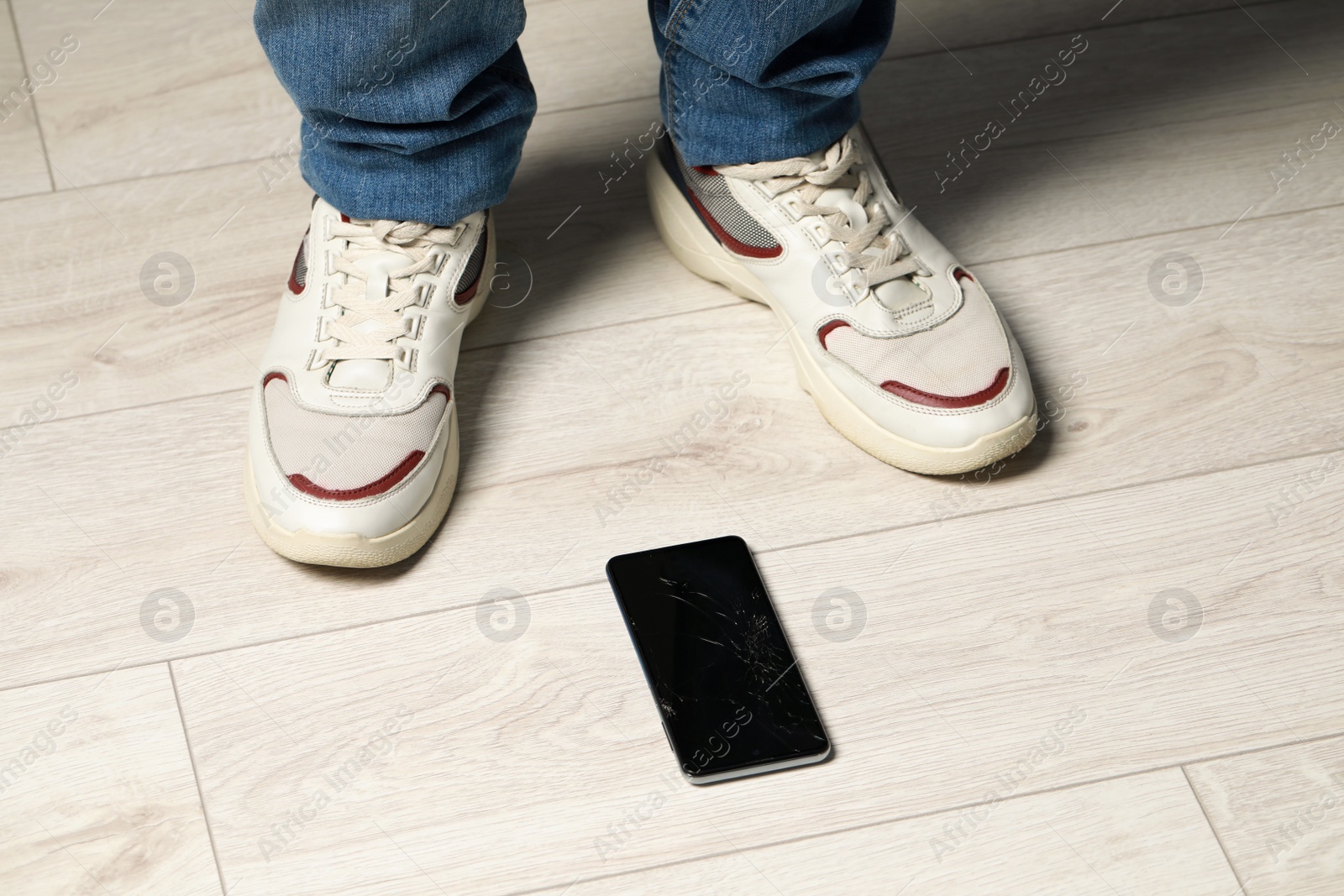 Photo of Man near dropped smartphone on floor, closeup. Device repairing