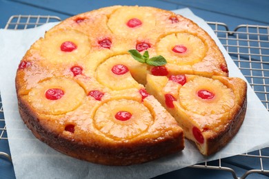 Delicious cut pineapple pie with cherry on blue table, closeup