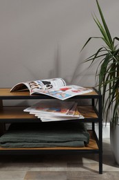 Photo of Wooden cabinet with magazines near houseplant indoors