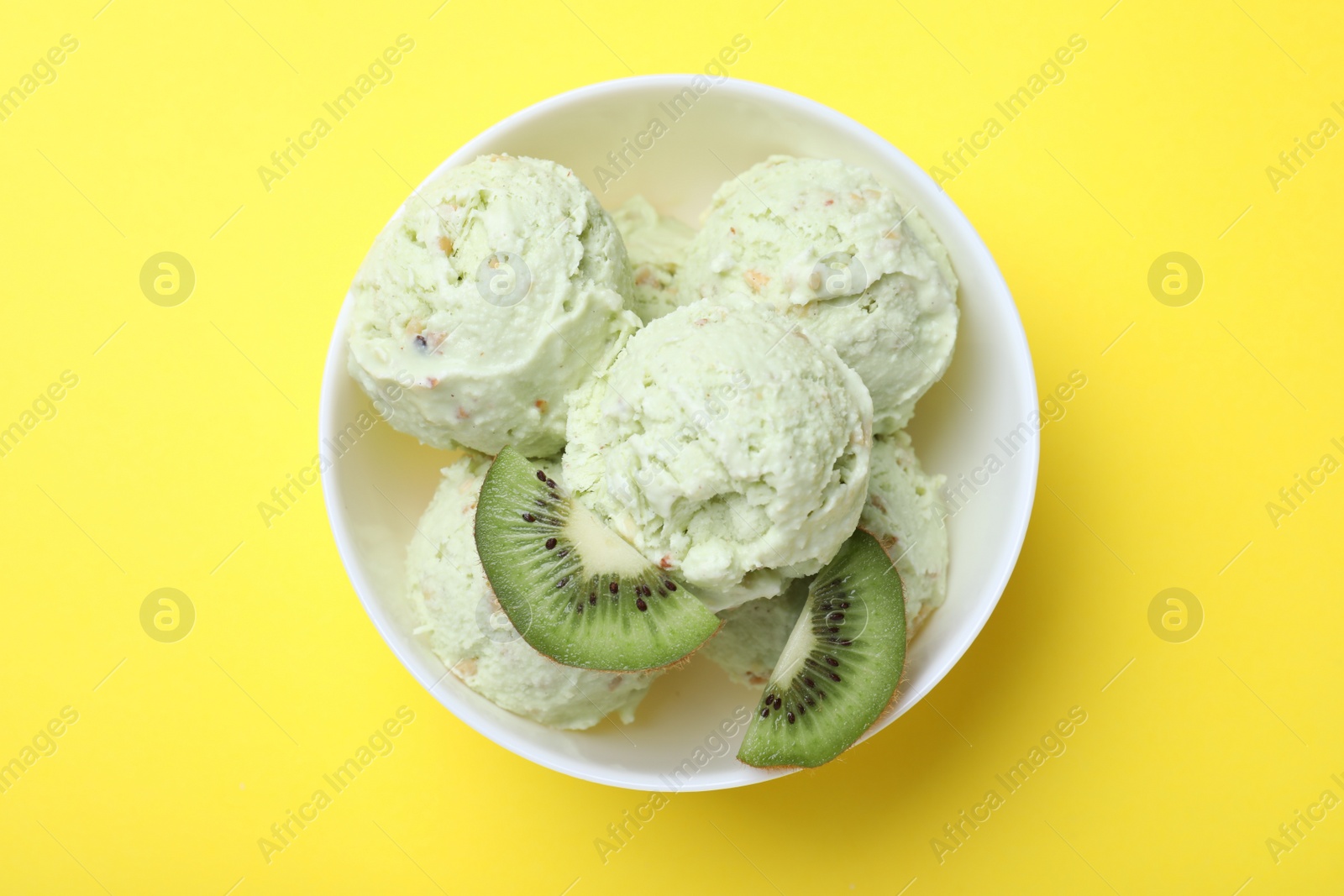 Photo of Delicious kiwi ice cream on yellow background, top view