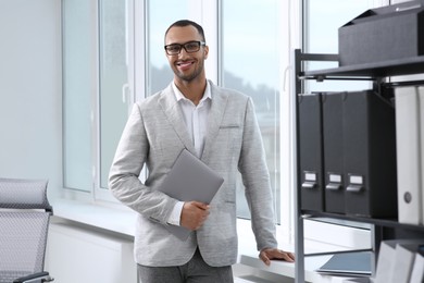 Photo of Smiling young businessman with laptop in modern office