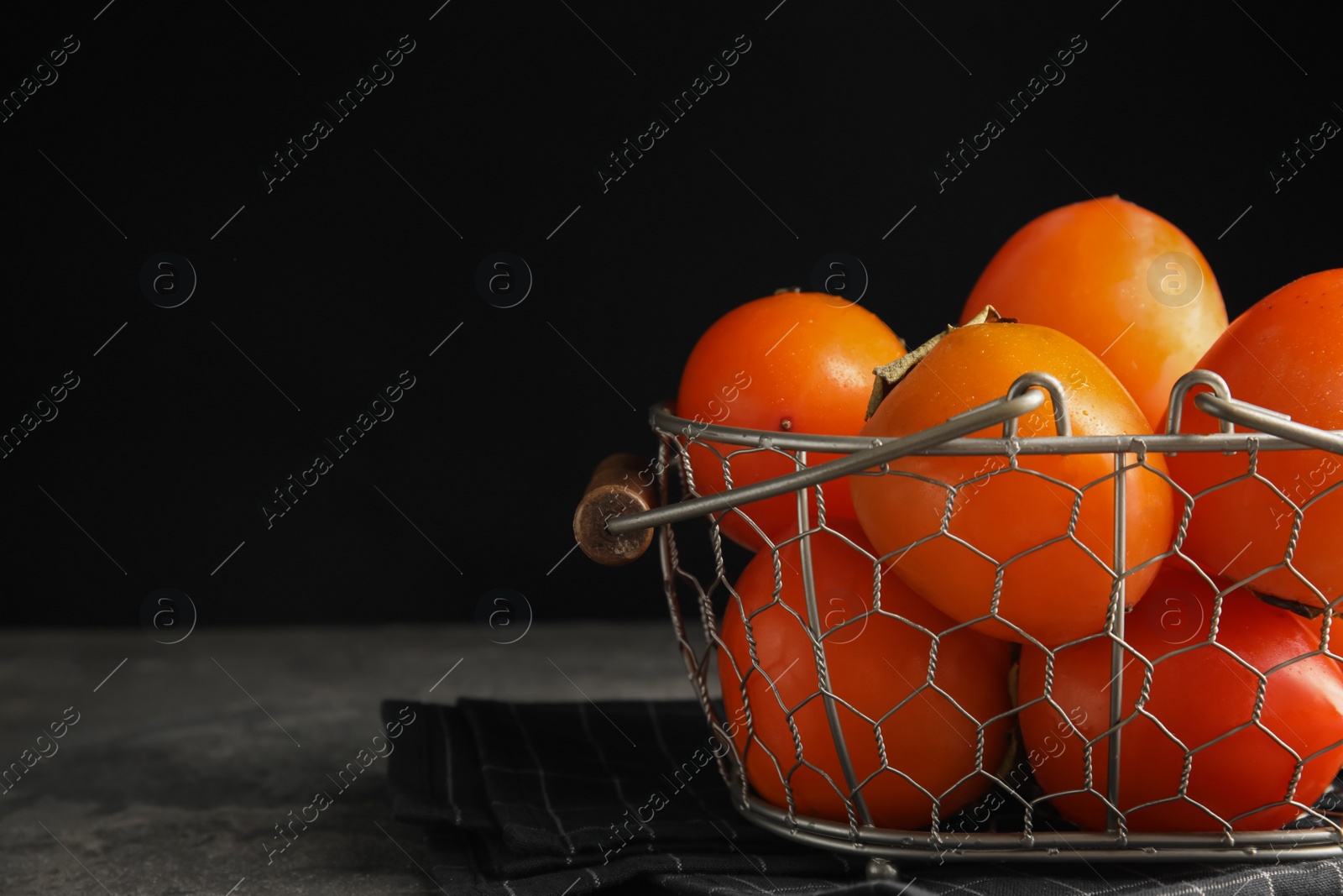 Photo of Delicious fresh persimmons on grey table, closeup. Space for text
