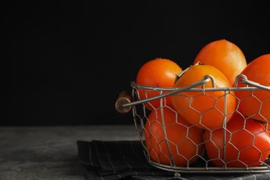 Delicious fresh persimmons on grey table, closeup. Space for text