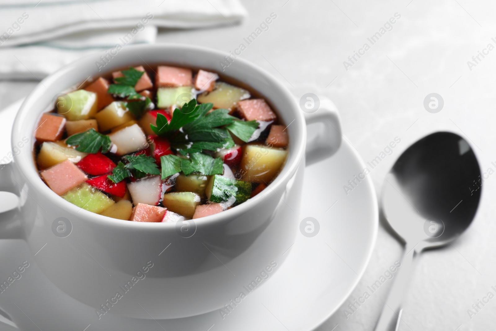 Photo of Delicious cold okroshka with kvass served on light grey table, closeup. Traditional Russian summer soup