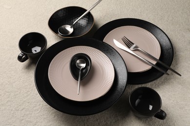 Stylish table setting. Dishes, cutlery and cups on light surface