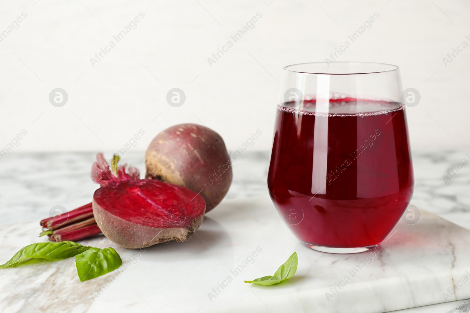 Photo of Glass with beet juice and fresh vegetable on table