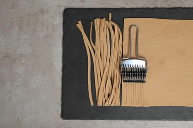 Photo of Uncooked homemade soba with dough and cutter on table, top view. space for text