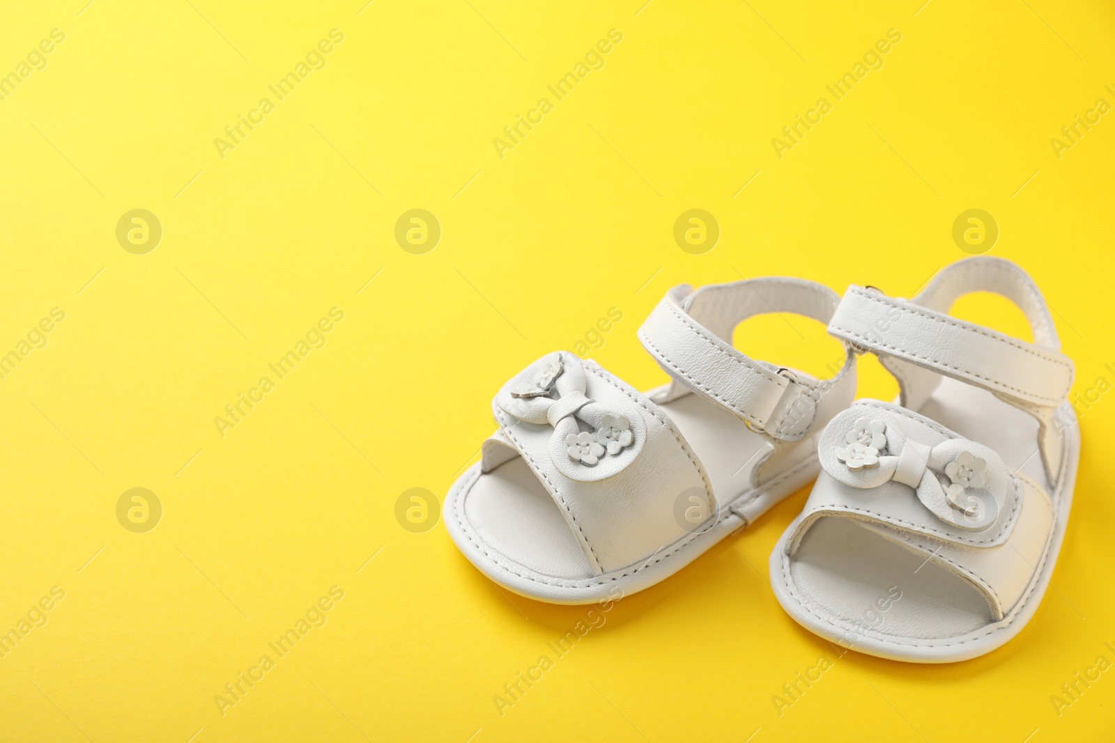 Photo of Pair of cute baby sandals on color background