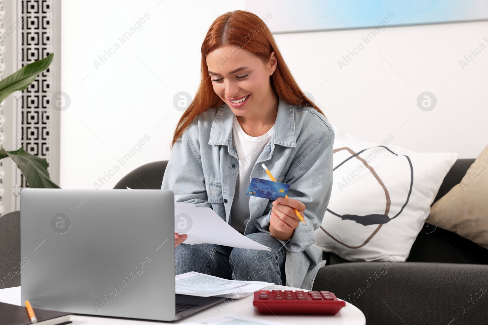 Photo of Woman with credit card using laptop for paying taxes online at home