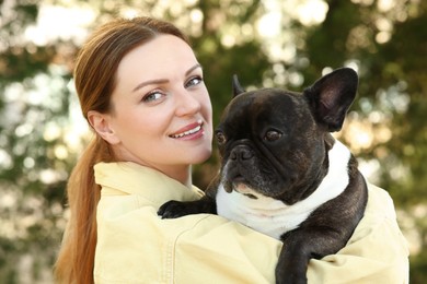 Portrait of happy woman with cute French Bulldog outdoors