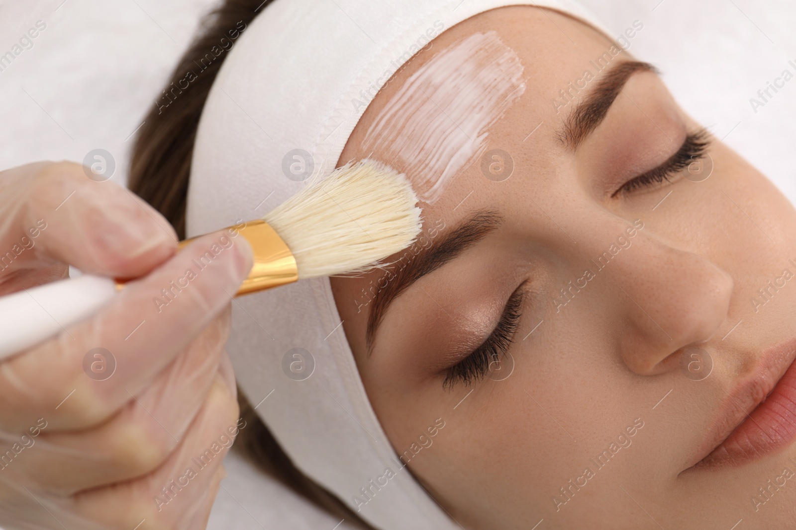 Photo of Young woman during face peeling procedure in salon, closeup