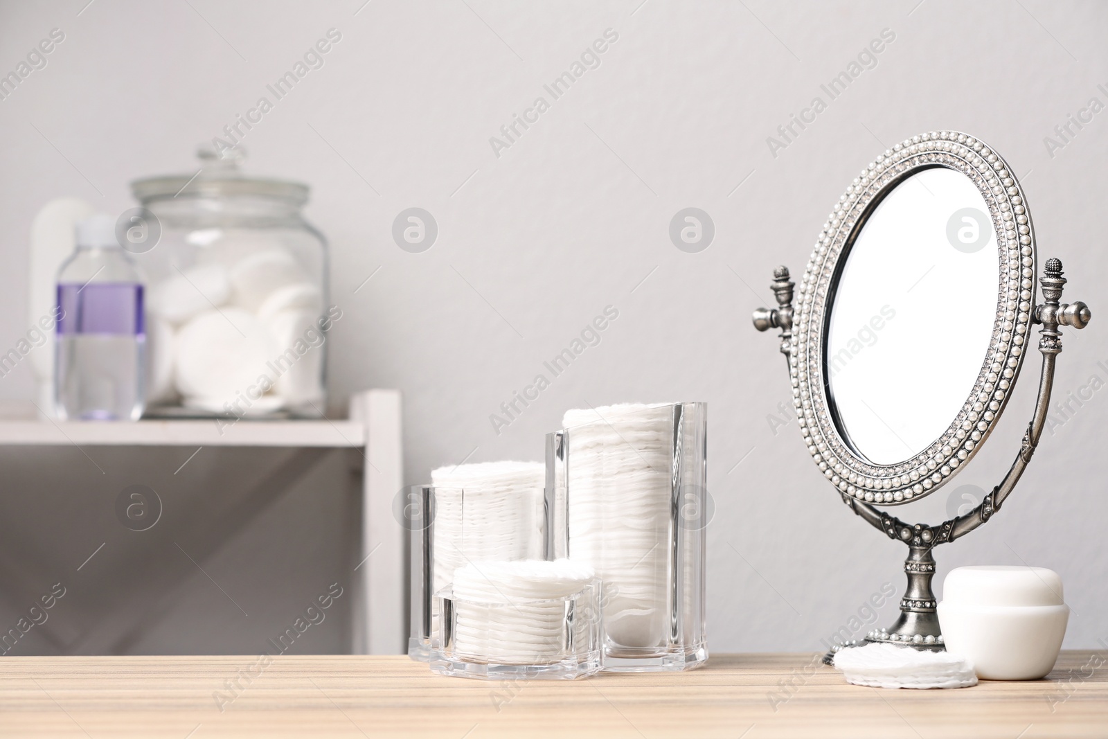 Photo of Cotton pads, mirror and cream on table in bathroom, space for text