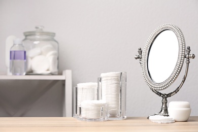 Photo of Cotton pads, mirror and cream on table in bathroom, space for text