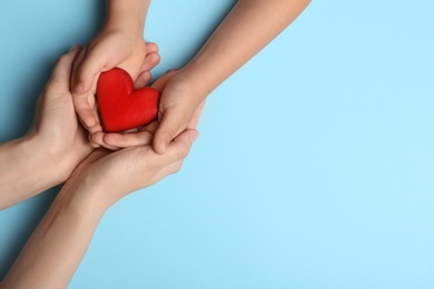 Woman and child holding heart on blue background, top view with space for text. Donation concept