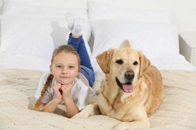 Cute child with her Labrador Retriever on bed at home. Adorable pet