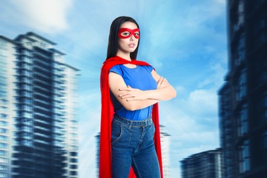 Confident young woman wearing superhero costume and beautiful cityscape on background