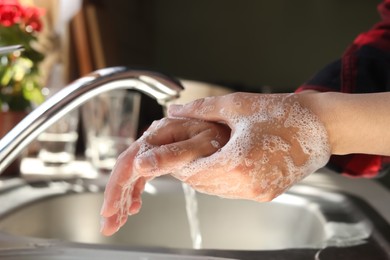 Photo of Woman washing hands in kitchen, closeup view