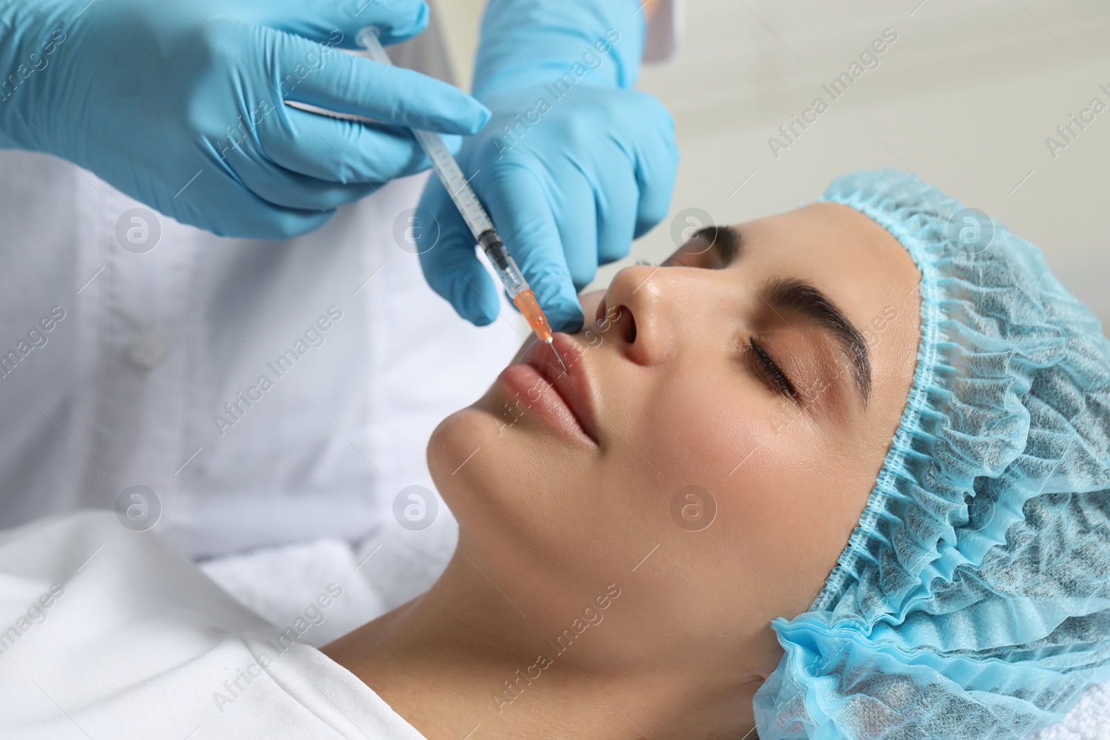 Photo of Doctor giving lips injection to young woman in clinic. Cosmetic surgery