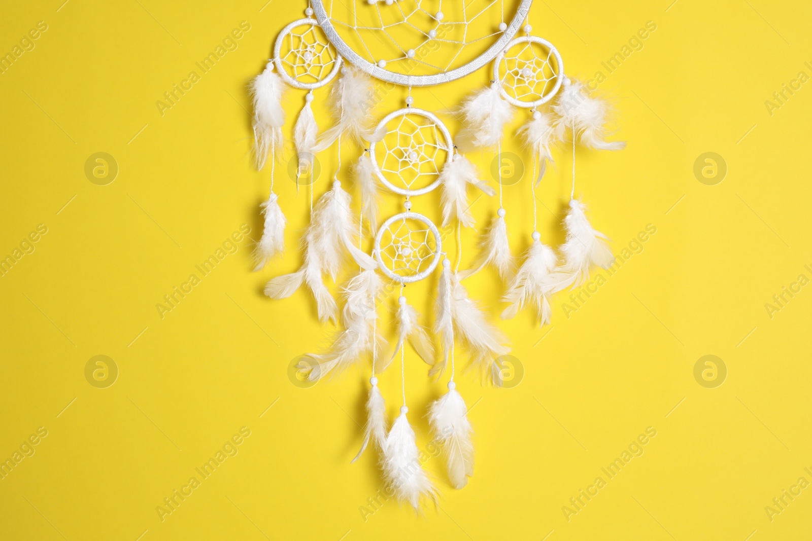 Photo of Beautiful dream catcher hanging on yellow background