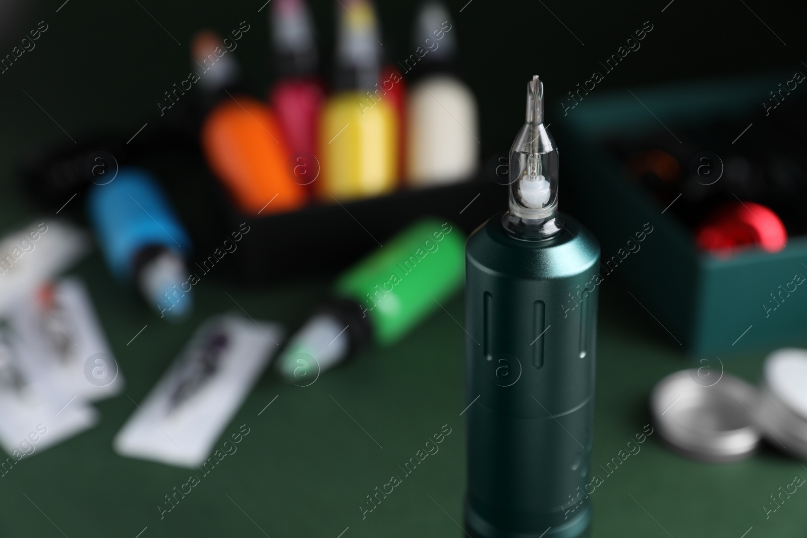 Photo of Tattoo machine and tools on dark green table, closeup