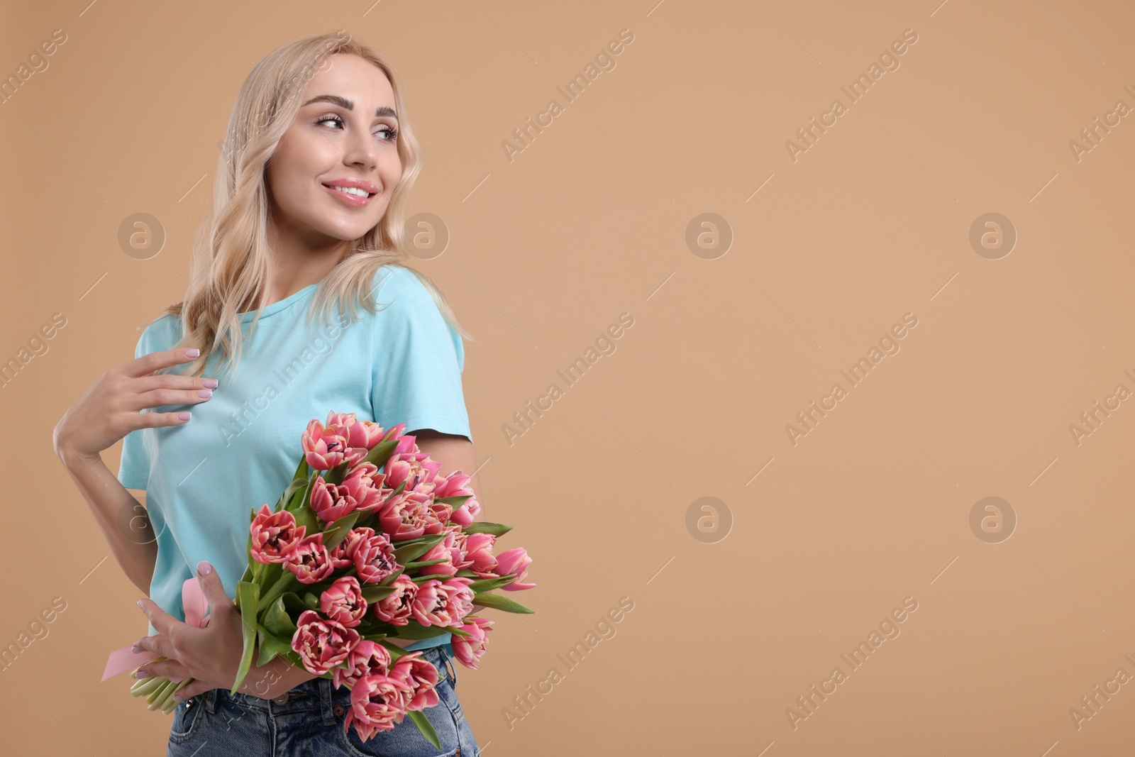 Photo of Happy young woman with beautiful bouquet on beige background. Space for text