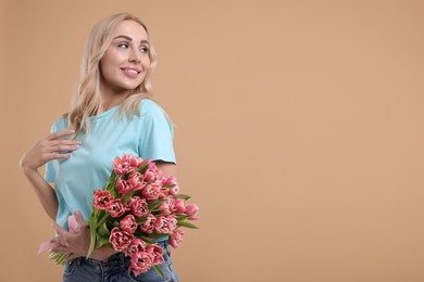 Happy young woman with beautiful bouquet on beige background. Space for text