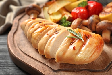 Fried chicken breast served with garnish on wooden board, closeup