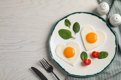 Photo of Heart shaped fried eggs served on white wooden table, flat lay. Space for text