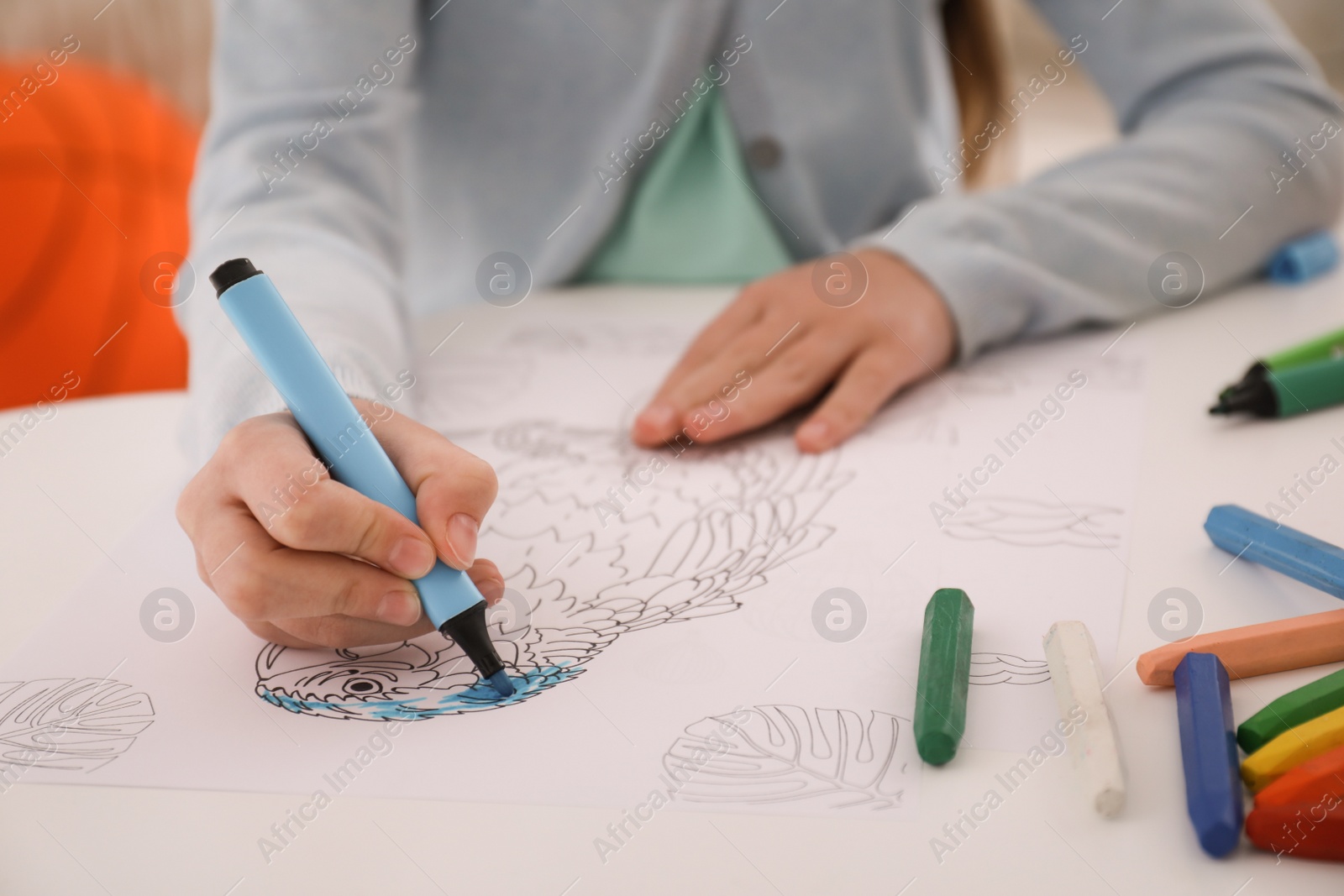 Photo of Child coloring drawing at table in room, closeup