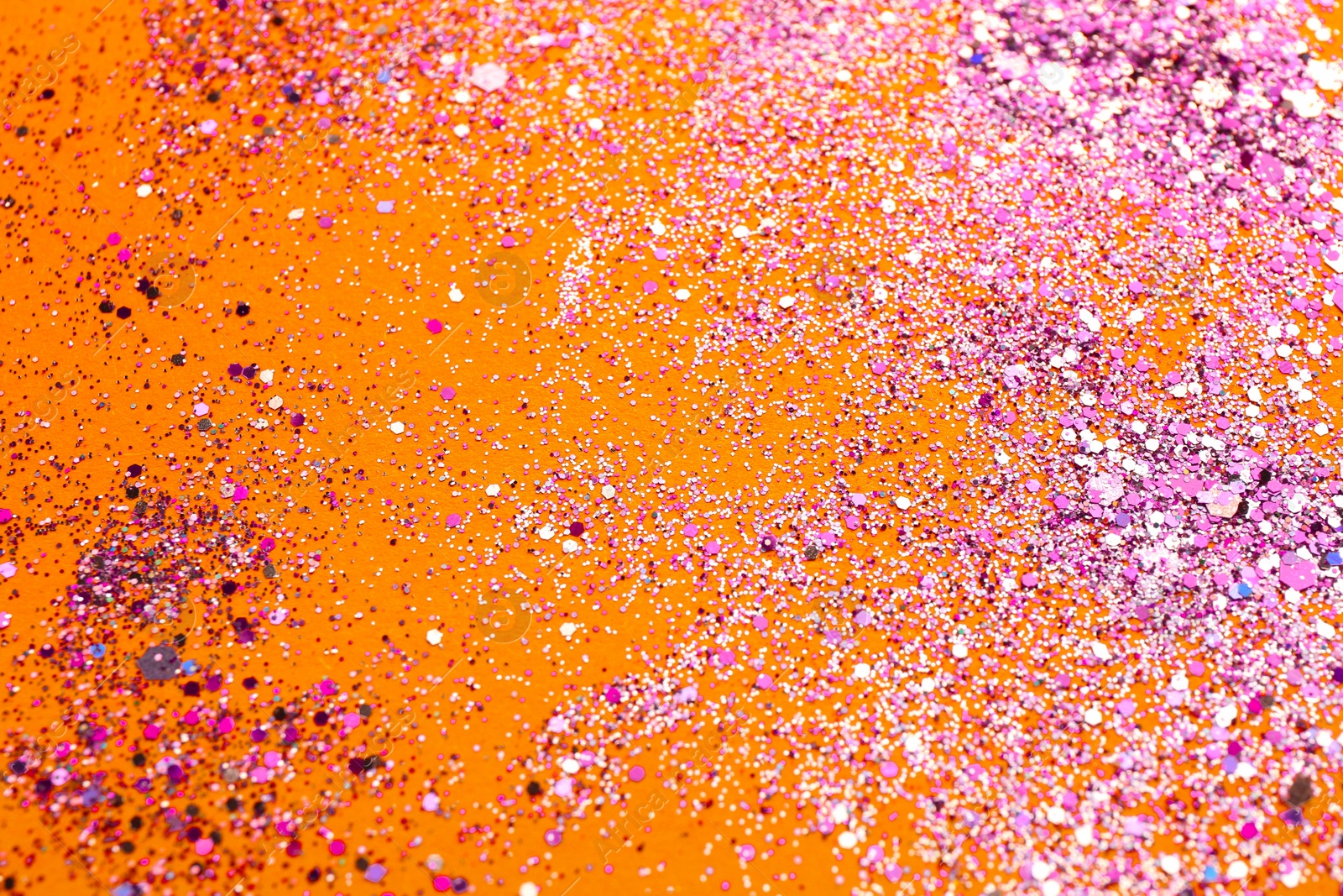 Photo of Shiny bright pink glitter on yellow background