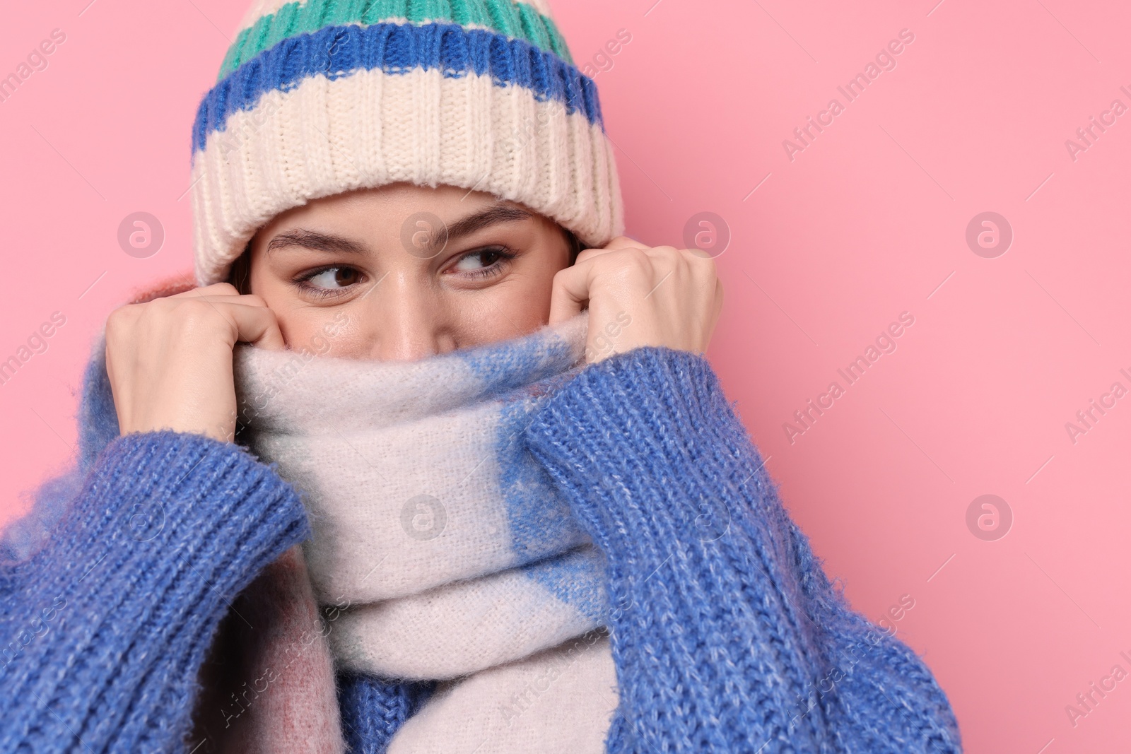 Photo of Beautiful woman in warm scarf and hat on pink background