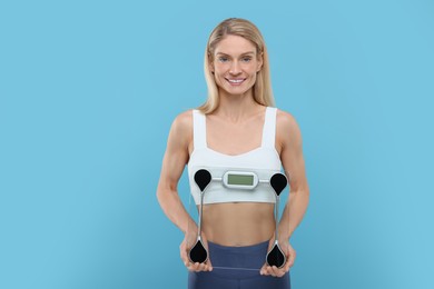 Photo of Slim woman holding scales on light blue background. Weight loss