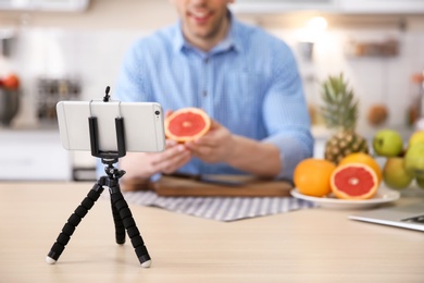 Young blogger with fruits recording video on kitchen