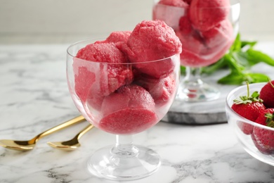 Photo of Delicious pink ice cream served with strawberries on marble table