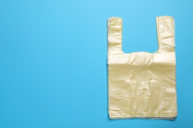 Photo of Pack of plastic bags on light blue background, top view. Space for text