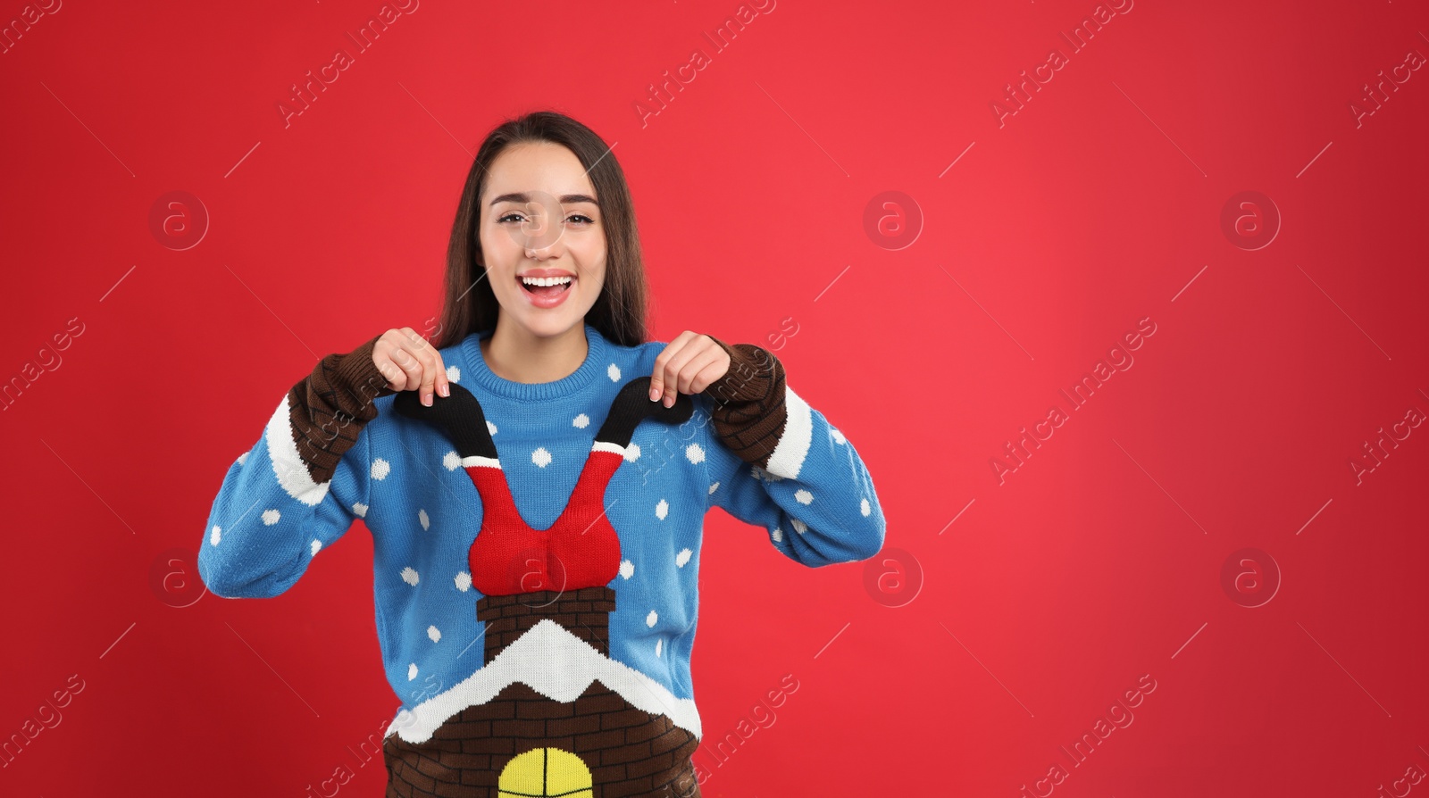 Photo of Young woman in Christmas sweater on red background, space for text