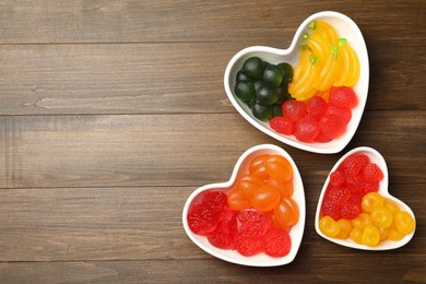 Delicious gummy fruit shaped candies on wooden table, flat lay. Space for text