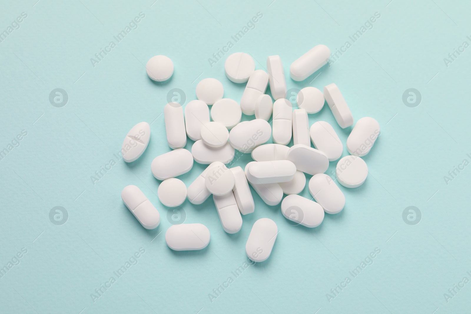 Photo of Pile of white pills on mint background, flat lay