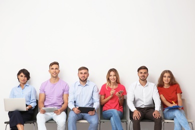 Photo of Group of young people waiting for job interview near light wall