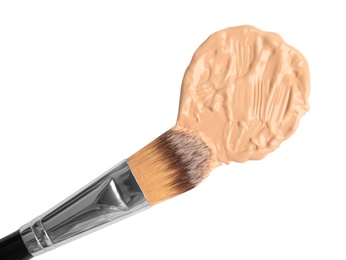 Photo of Sample of liquid foundation and makeup brush on white background, top view