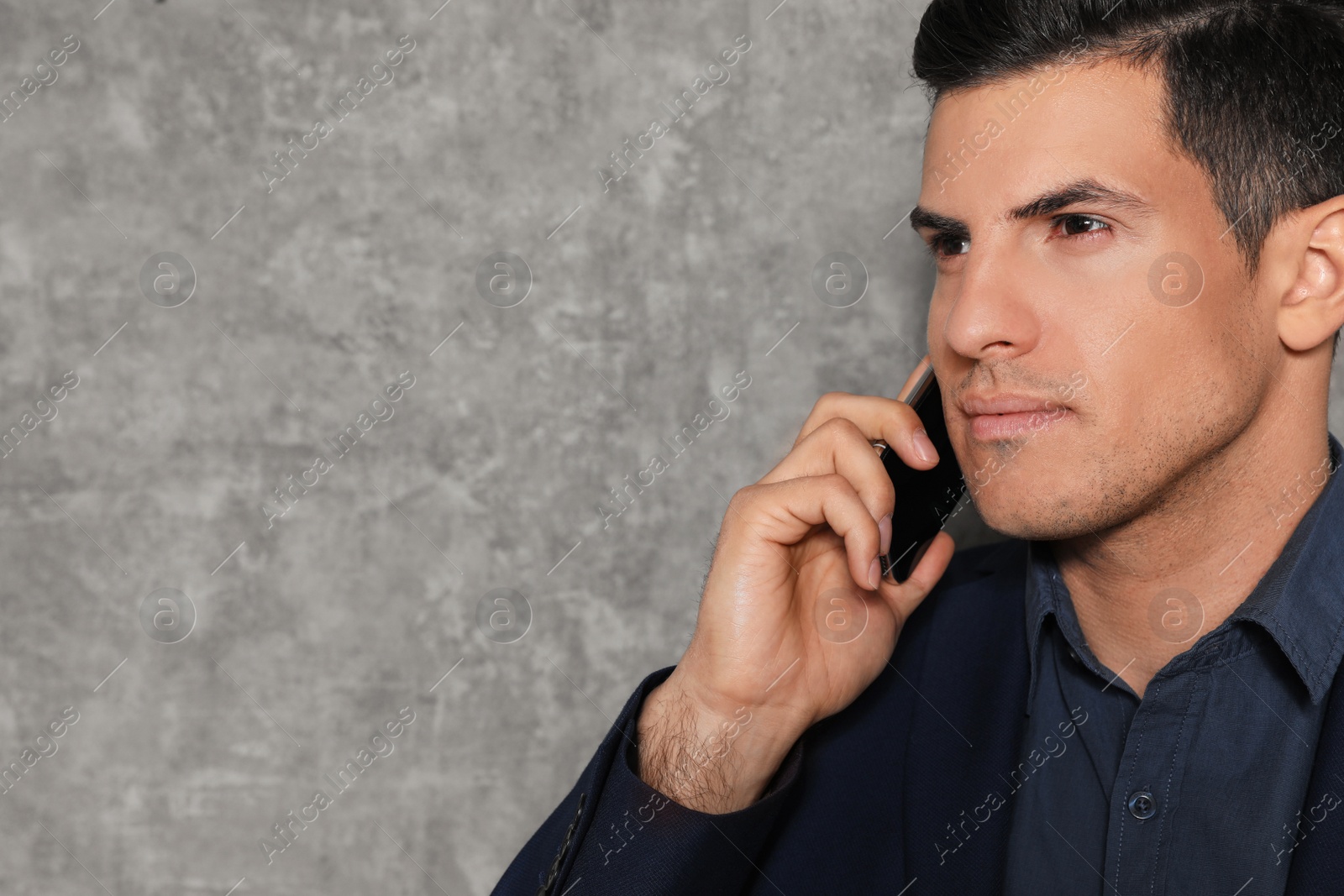 Photo of Portrait of businessman talking on phone against grey background, closeup. Space for text