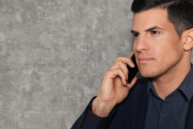 Portrait of businessman talking on phone against grey background, closeup. Space for text