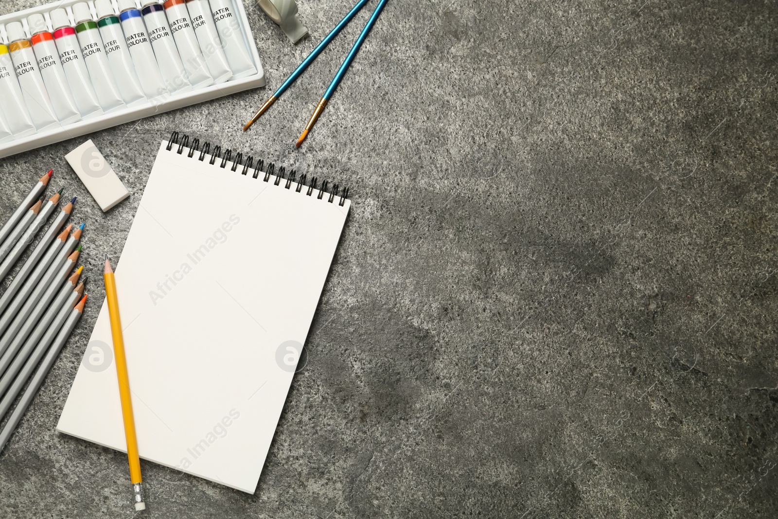 Photo of Flat lay composition with blank sketchbook on grey stone table. Space for text