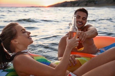 Photo of Happy young couple on inflatable rings in water